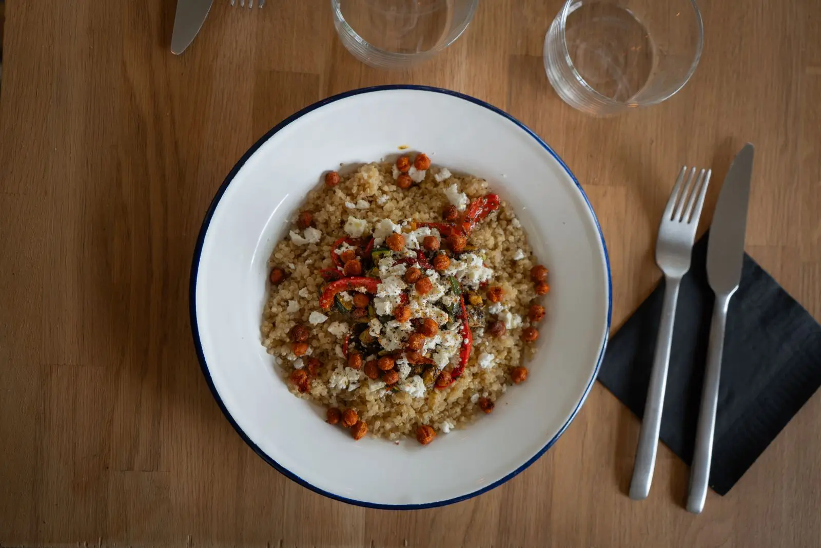 Quinoa salad with chickpeas, red peppers and feta on a wooden table