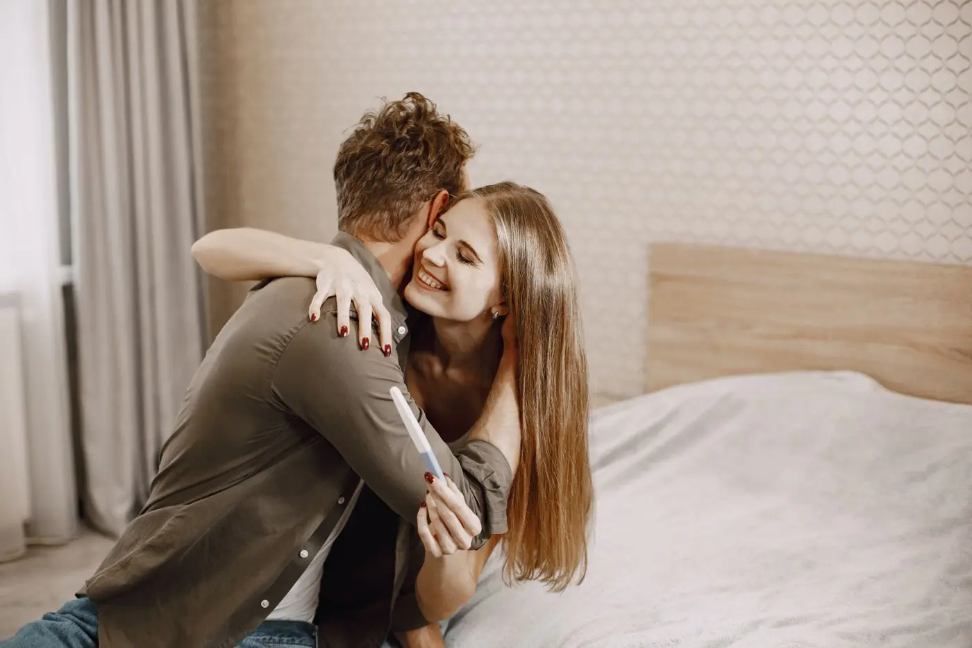 Couple embracing while holding a positive pregnancy test