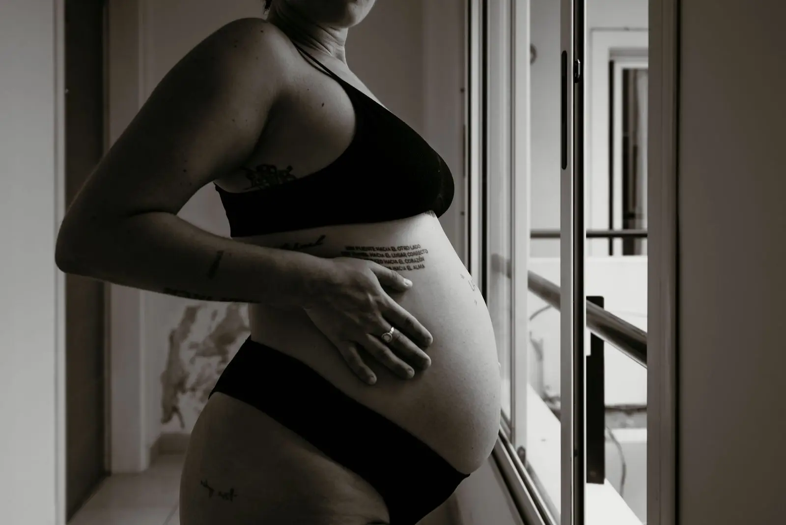 Black and white portrait of a woman gently holding her belly