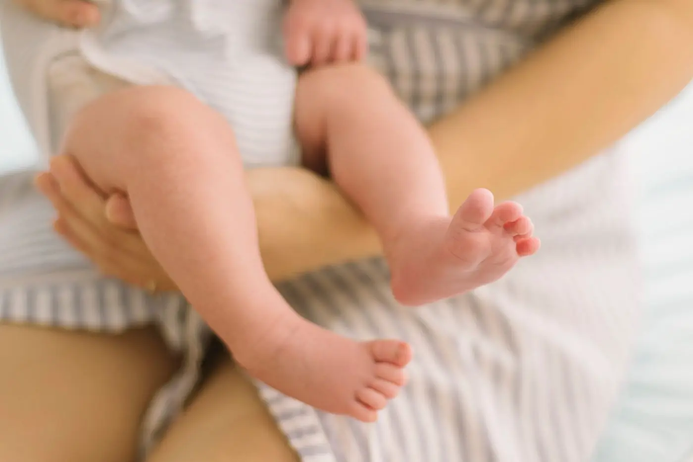 Mother holding her newborn's feet in a blanket