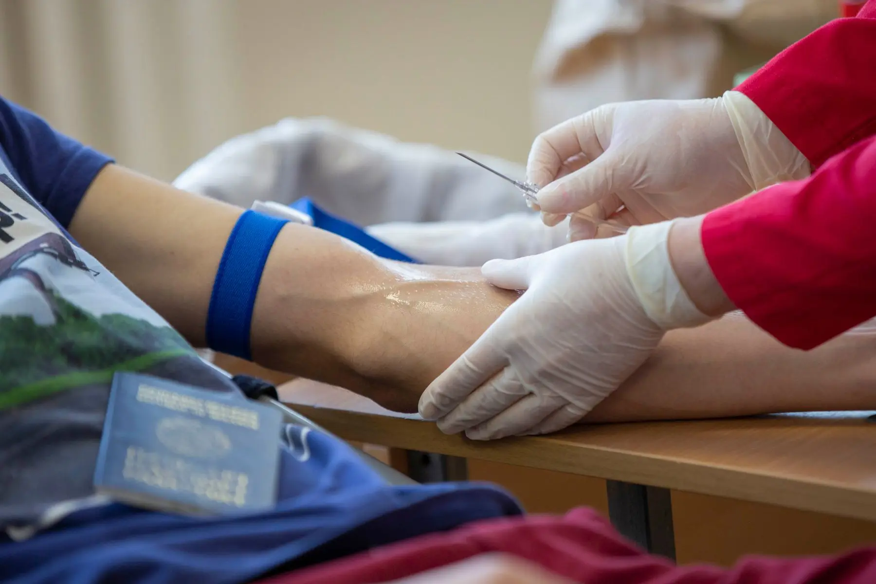 Healthcare worker in gloves preparing to draw a blood sample from a patient's arm