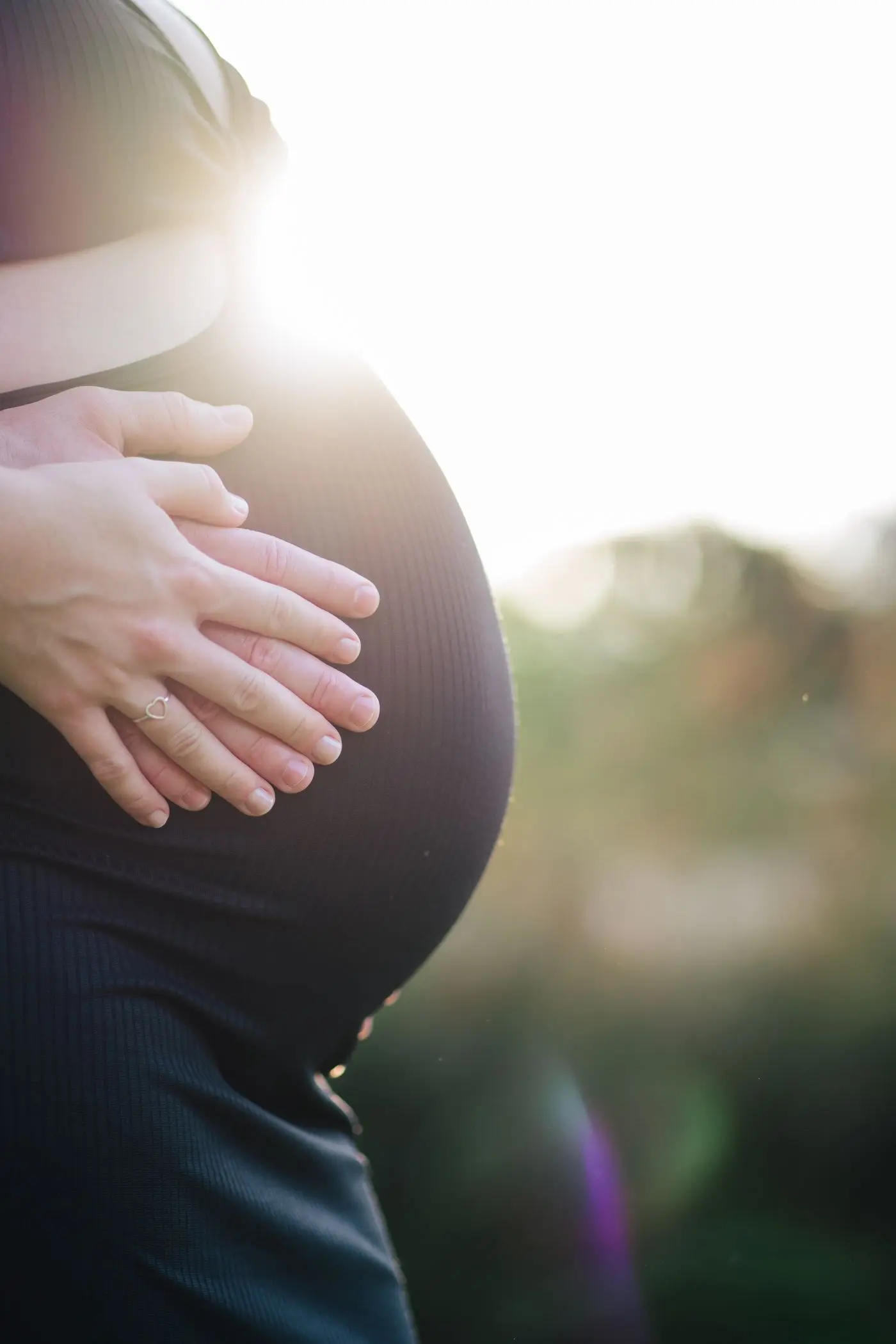 Expecting mother holding her bump in warm sunlight