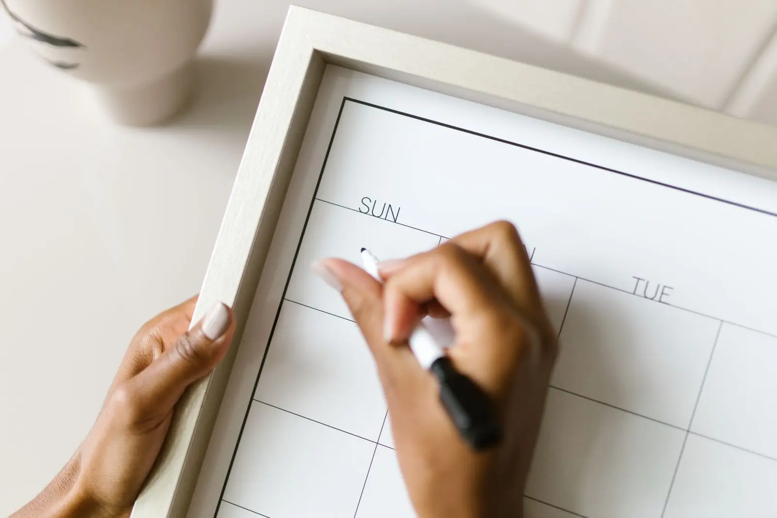Hands writing on a wall calendar with a marker to plan the fertile window