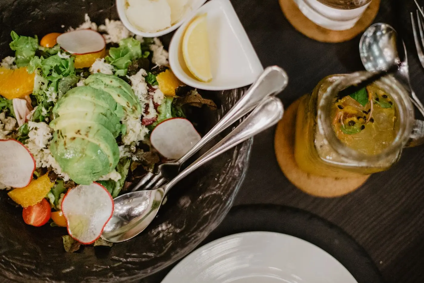 Fresh salad with avocado and a glass of juice on a wooden table