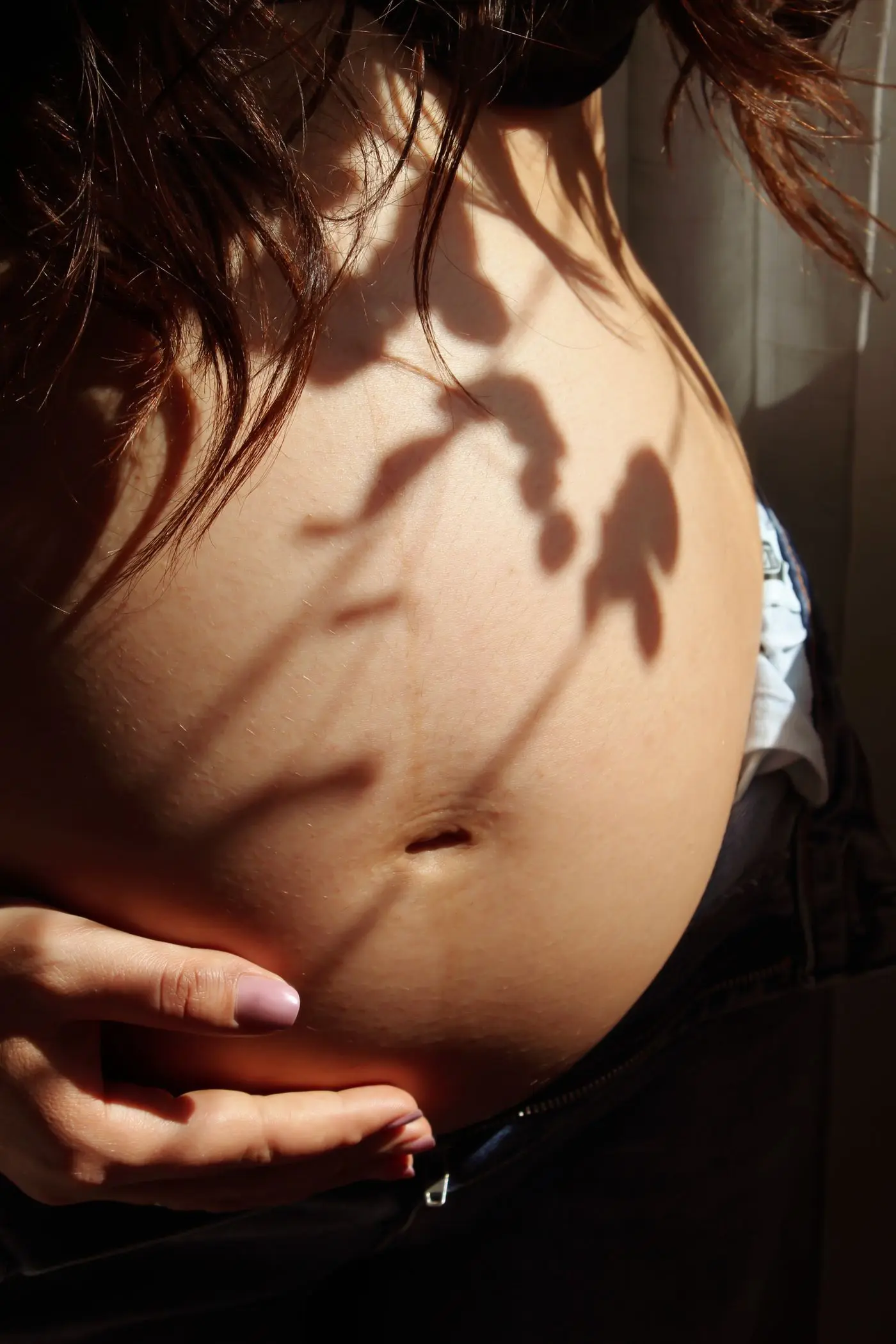 Leaf shadows falling on a pregnant belly