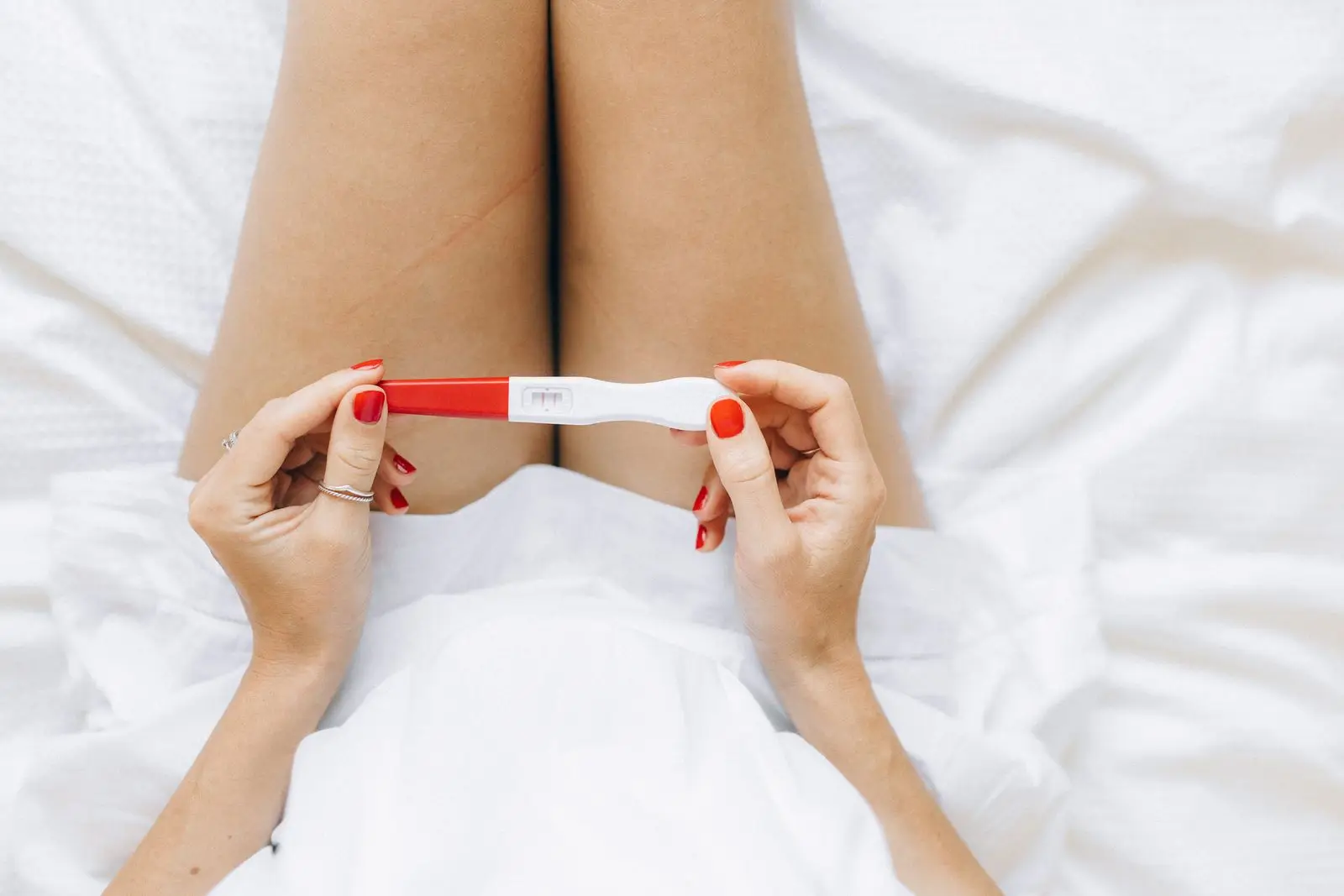 Woman's hands holding a positive pregnancy test with two lines