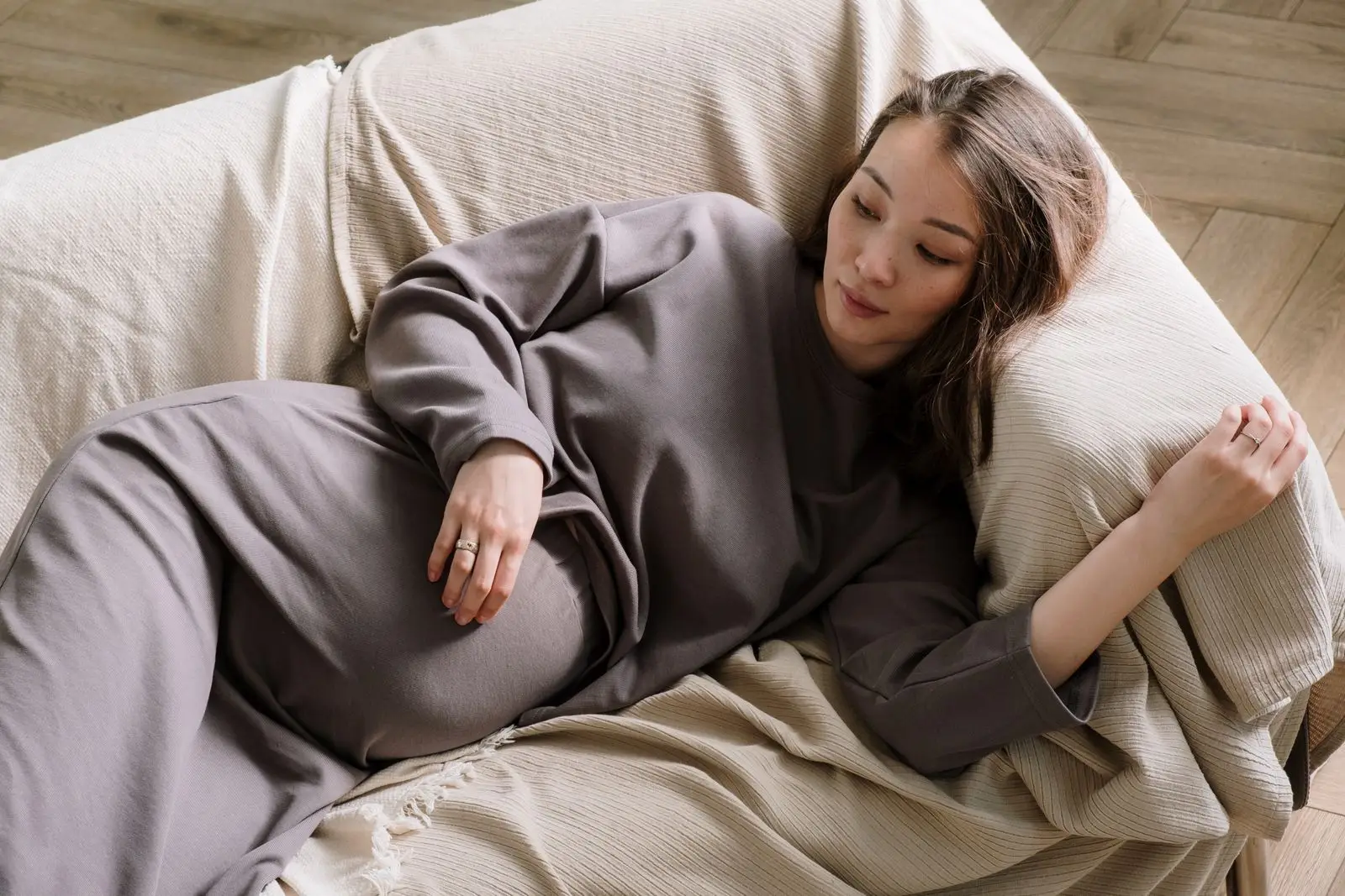 Pregnant woman lying on a sofa resting to manage early pregnancy tiredness