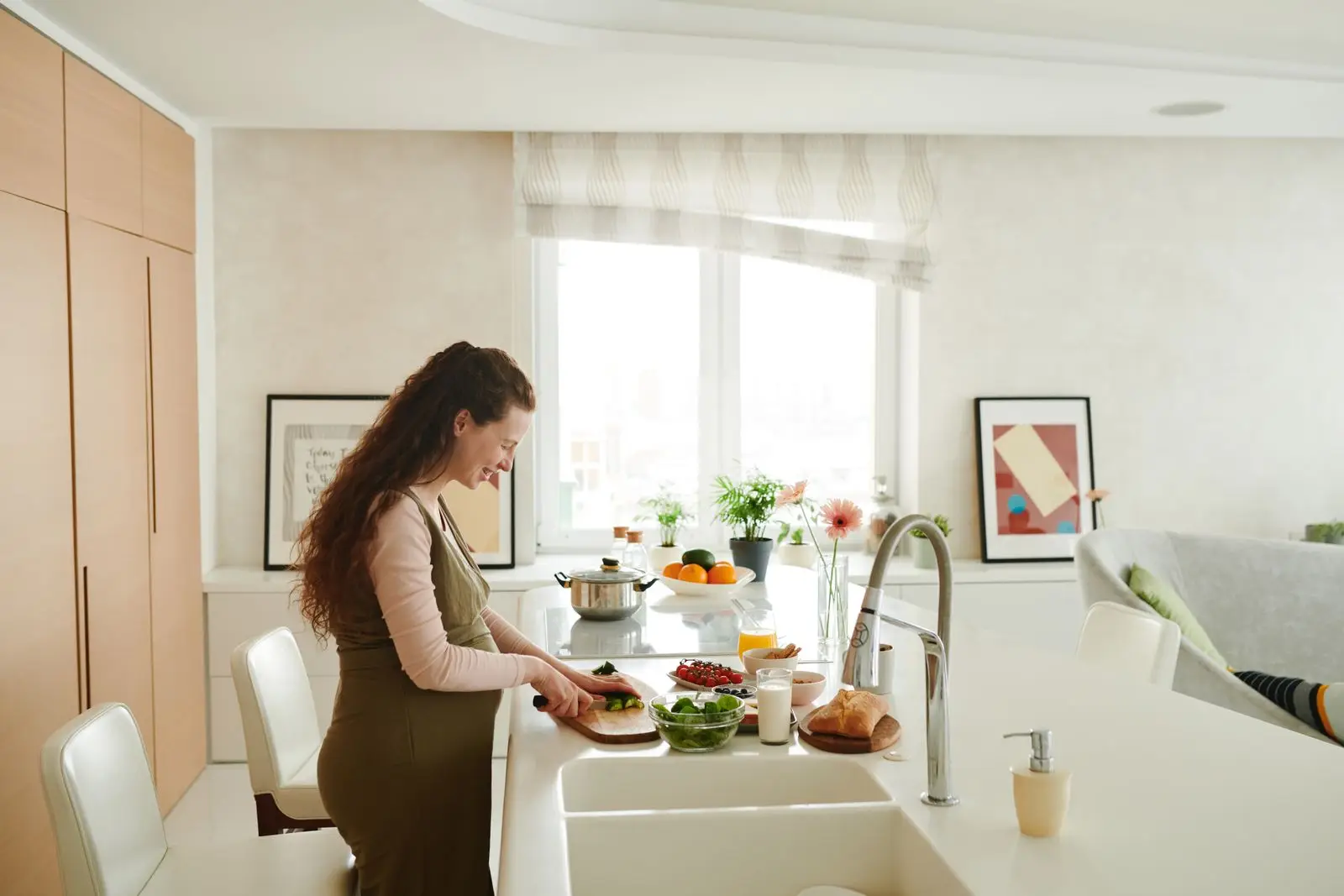 Pregnant woman slicing fresh vegetables in a bright kitchen