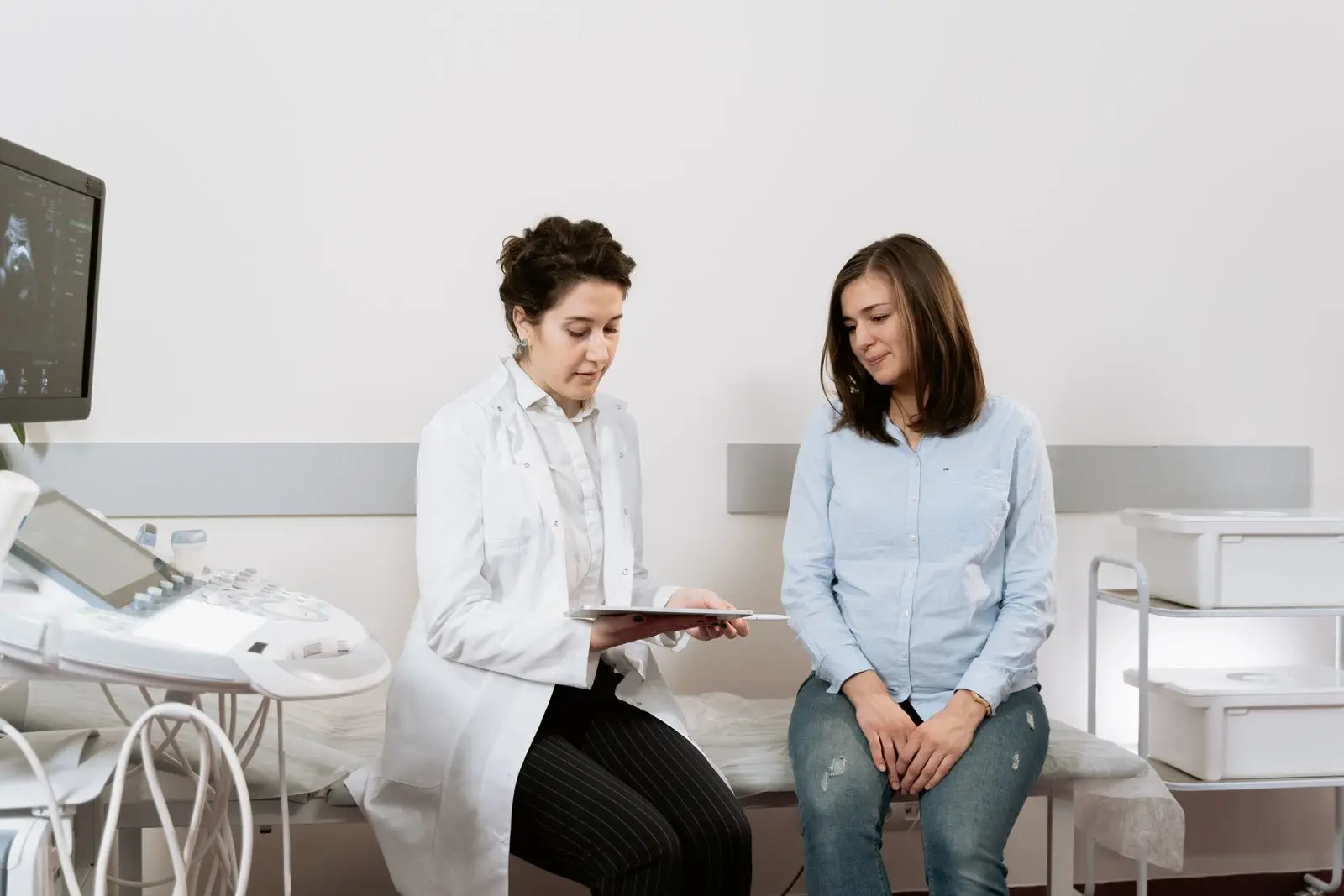 Pregnant woman at a first prenatal visit talking with her doctor