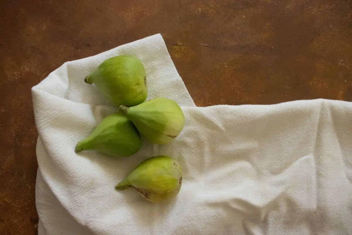 Four ripe green figs on a white cloth, about the size of your baby at 11 weeks pregnant