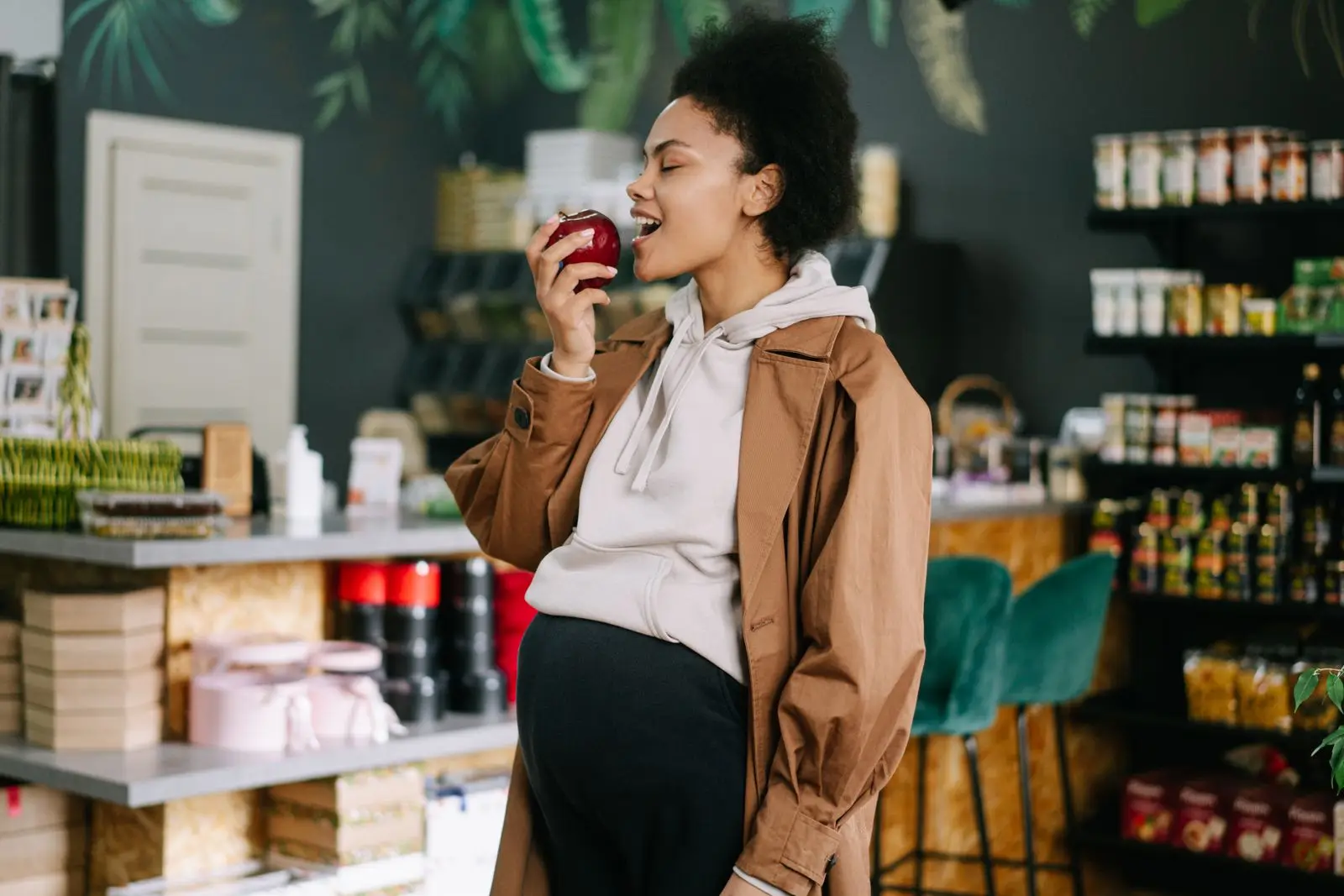 Pregnant woman holding a fresh apple in a grocery store