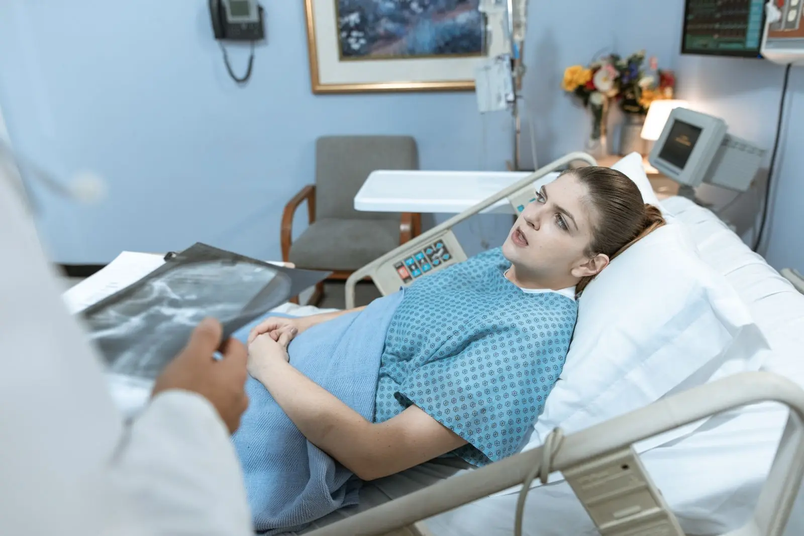 Woman in a hospital bed receiving care from a healthcare professional