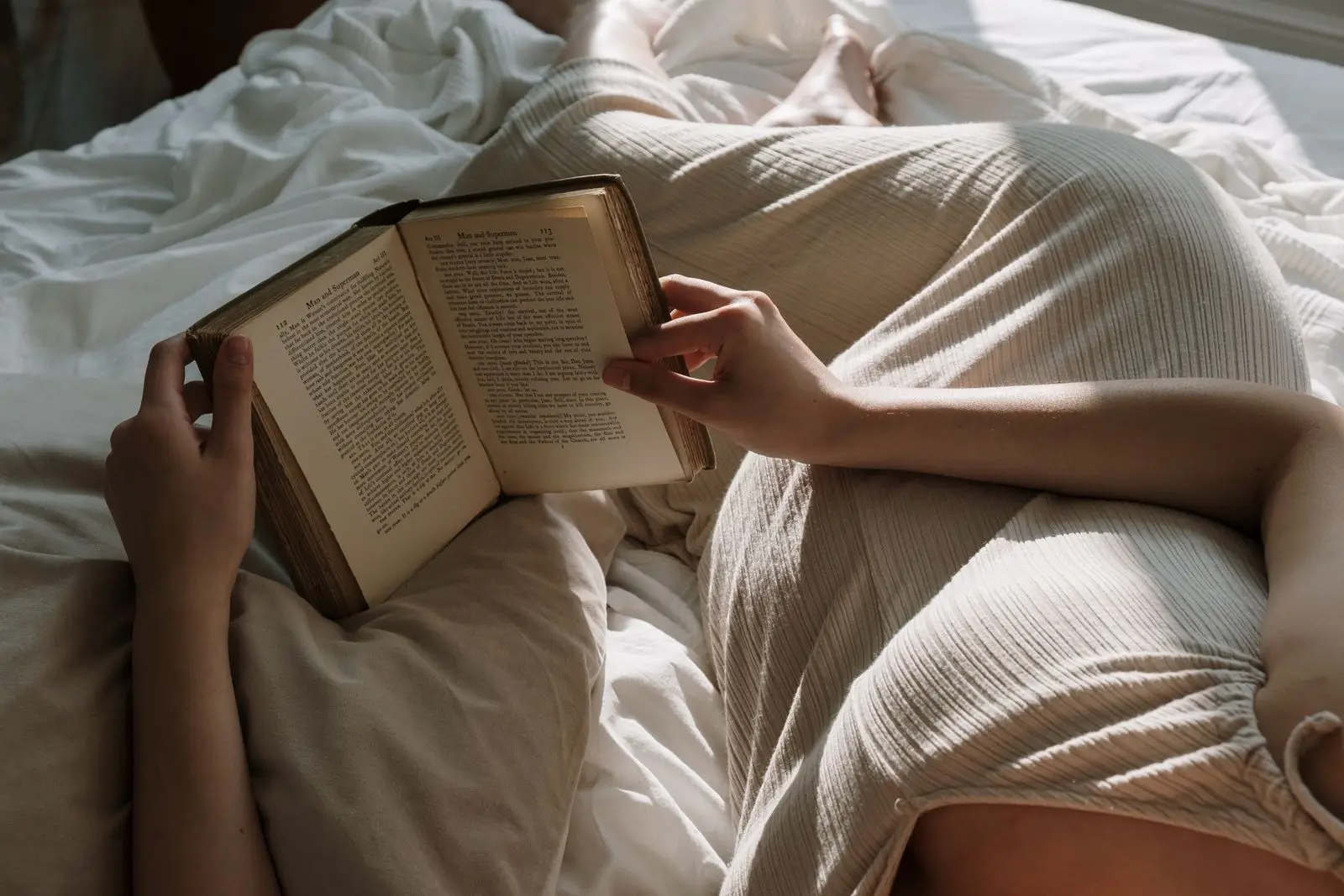 Pregnant woman reading a book in bed before sleep