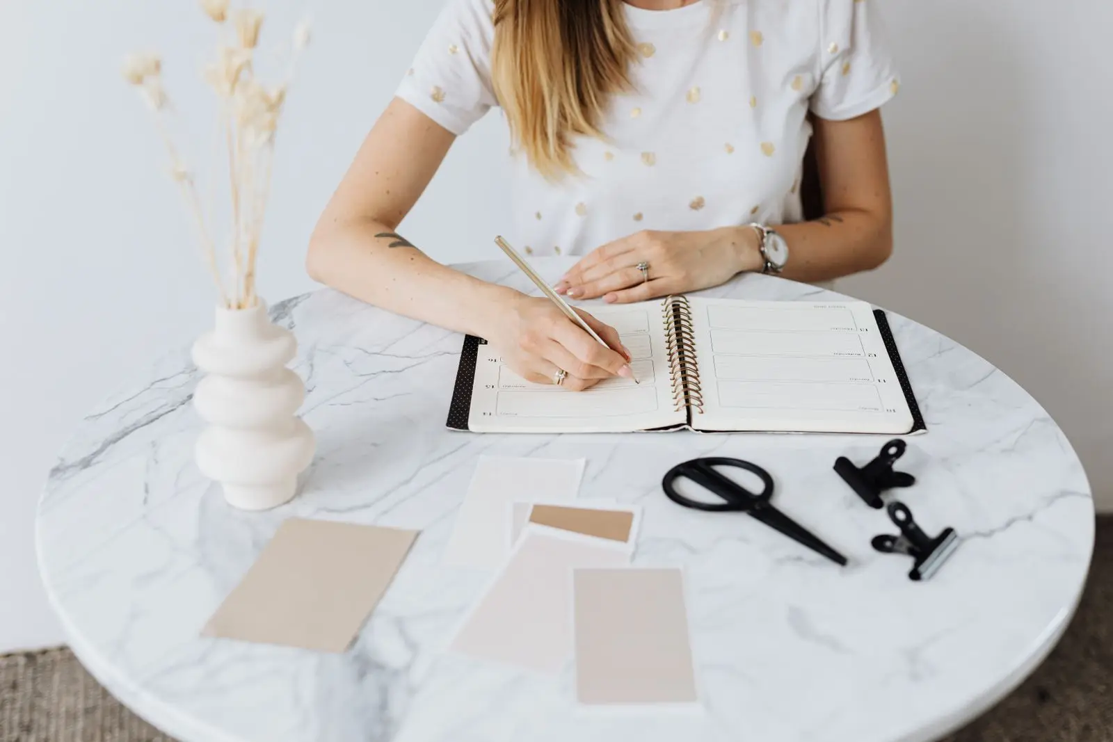 Woman writing in a planner on a marble table while preparing a birth plan
