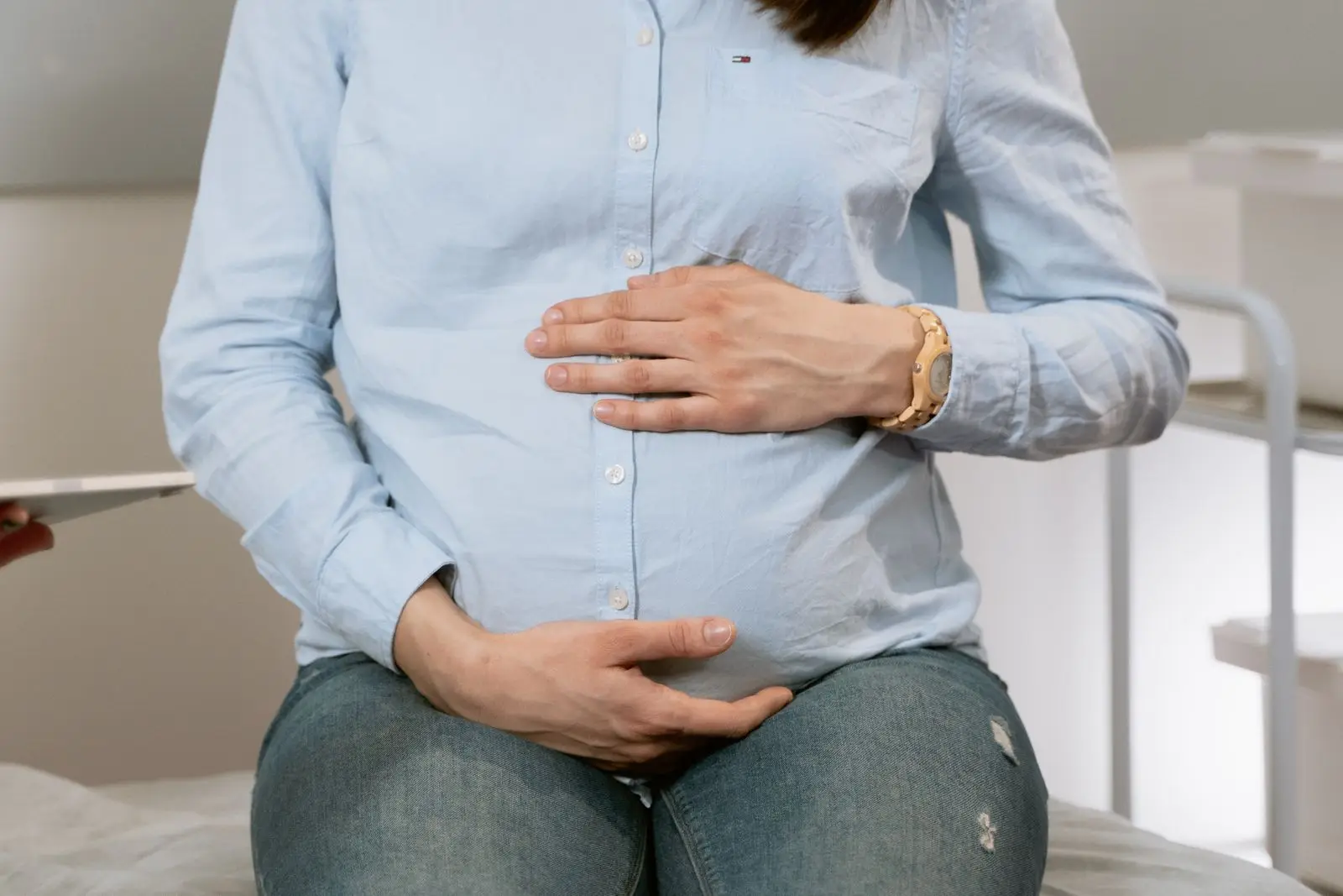 Pregnant woman with her hands on her belly at a prenatal checkup