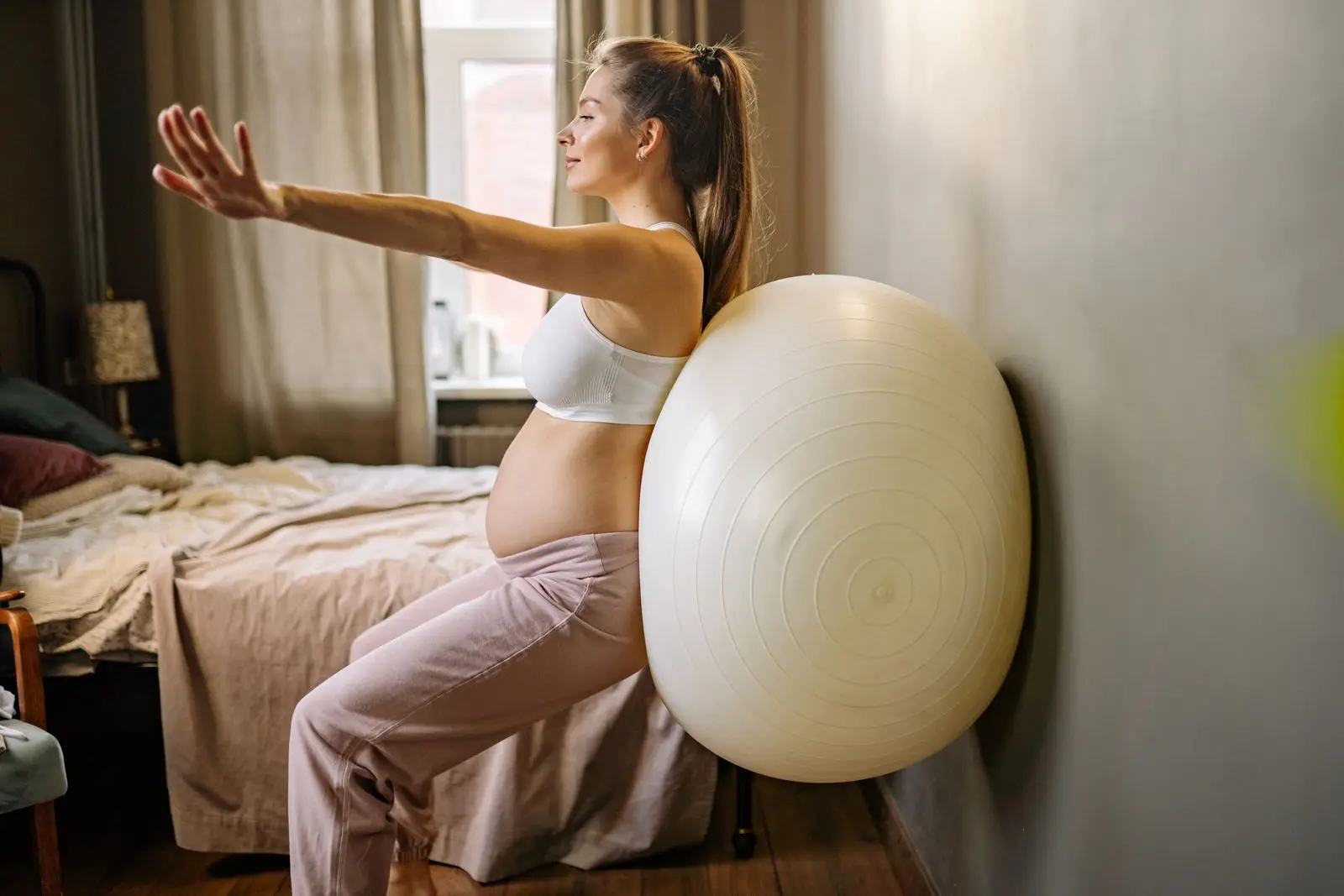 Pregnant woman using a stability ball at home to prepare for labour